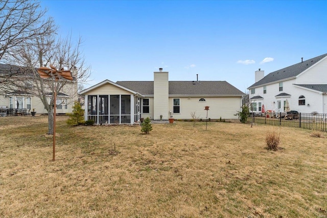 back of house featuring a sunroom, a yard, a chimney, and fence