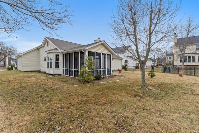 back of property with a yard, a chimney, fence, and a sunroom