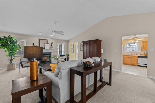 living room featuring light carpet, ceiling fan, vaulted ceiling, and a high end fireplace