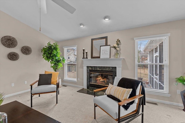 living area with light carpet, a healthy amount of sunlight, a premium fireplace, and baseboards