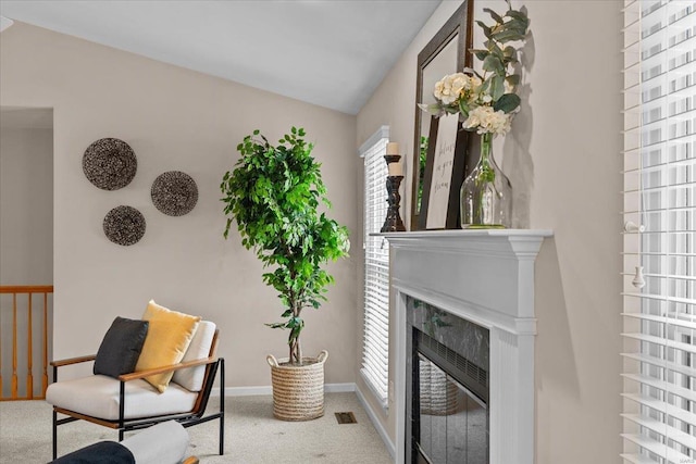 sitting room with lofted ceiling, visible vents, a high end fireplace, baseboards, and carpet