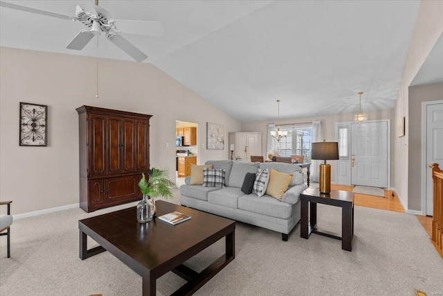 living area with a notable chandelier, vaulted ceiling, light carpet, and baseboards