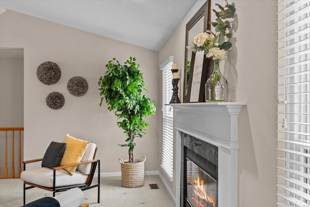 sitting room featuring visible vents, baseboards, lofted ceiling, carpet floors, and a fireplace