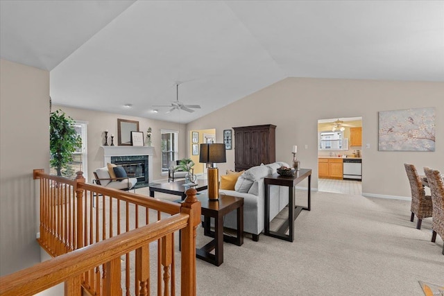 living area with a fireplace, lofted ceiling, a ceiling fan, light carpet, and baseboards