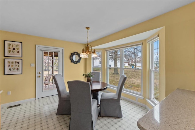 dining space with baseboards, visible vents, and a chandelier