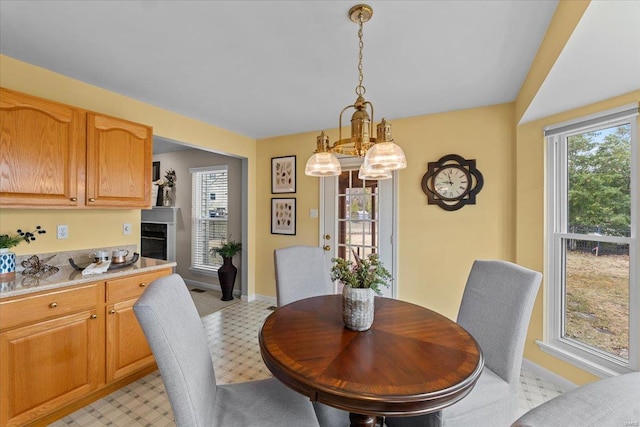 dining room featuring light floors, baseboards, and an inviting chandelier