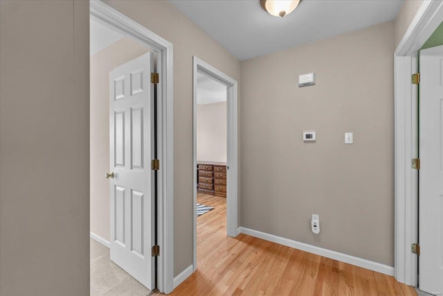 corridor with light wood-style flooring and baseboards