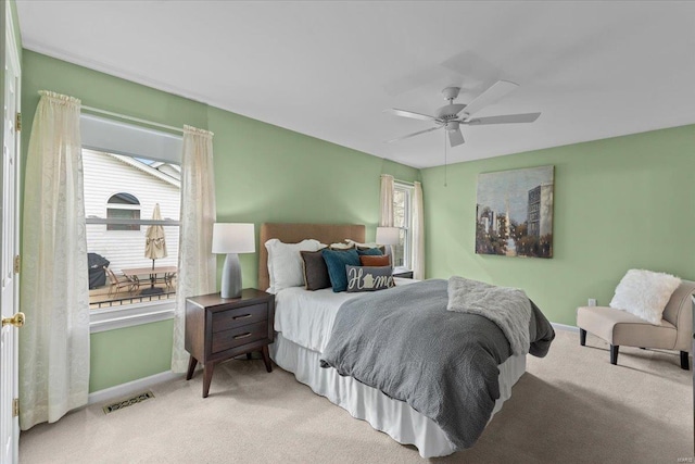 carpeted bedroom featuring a ceiling fan, visible vents, and baseboards