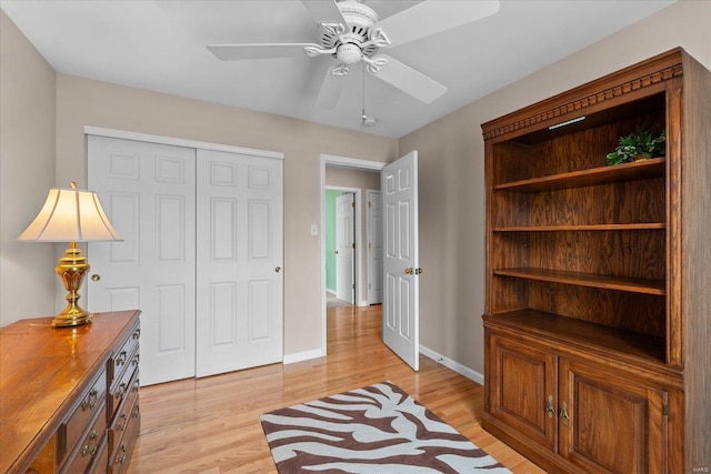 living area featuring light wood-type flooring, a ceiling fan, and baseboards