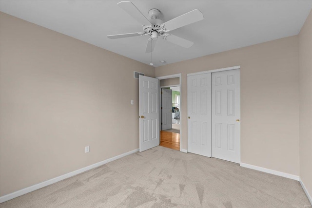 unfurnished bedroom featuring a closet, light carpet, visible vents, and baseboards