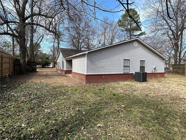 view of side of property featuring a yard, central AC, and fence