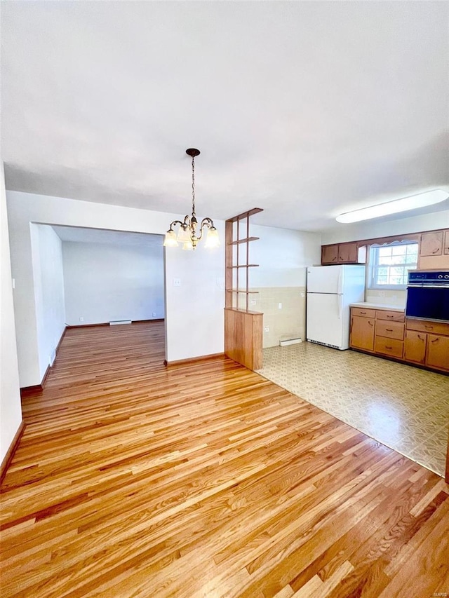 unfurnished dining area with a notable chandelier, baseboards, and light wood-style floors