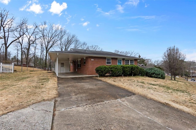 single story home featuring a carport, brick siding, concrete driveway, and fence