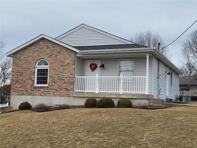 view of front of house with covered porch, central AC unit, a front lawn, and brick siding