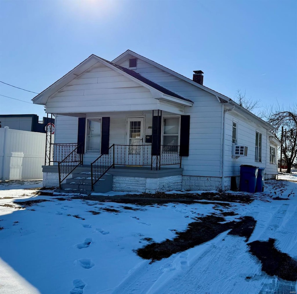 bungalow with a porch, cooling unit, fence, and a chimney