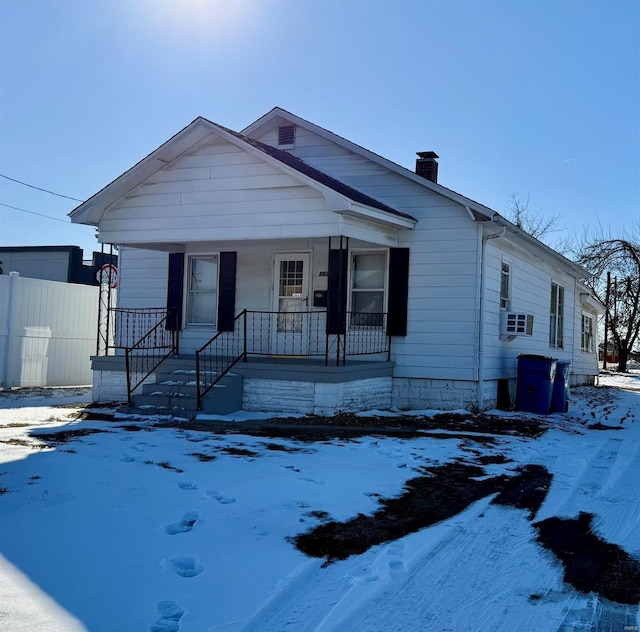 bungalow with a porch, cooling unit, fence, and a chimney