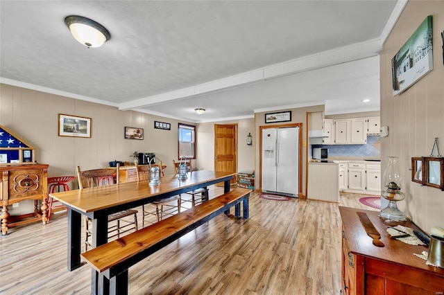 dining space with ornamental molding and light wood finished floors