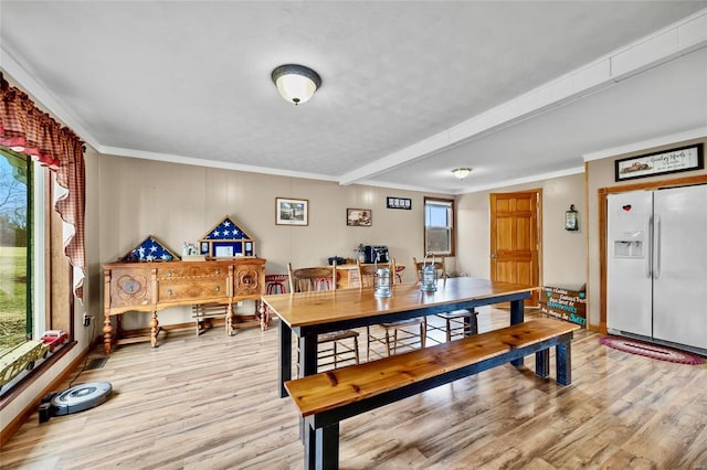 dining room with baseboards, light wood finished floors, and crown molding