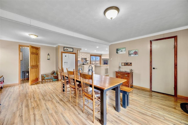 dining space featuring baseboards, light wood-style flooring, and crown molding