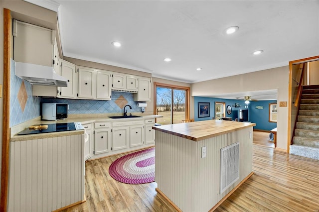 kitchen featuring crown molding, white microwave, wood counters, and light wood-style floors