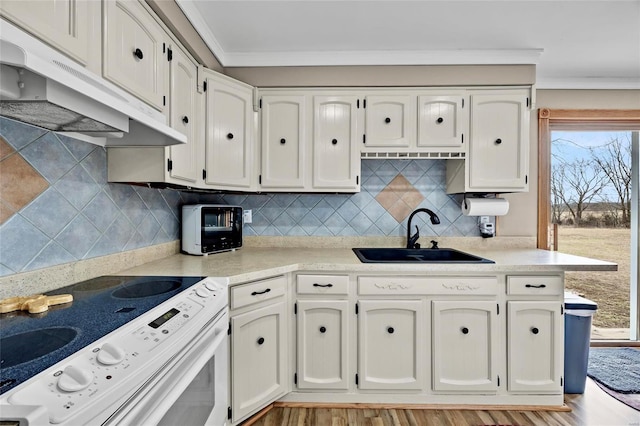 kitchen with under cabinet range hood, a sink, white cabinetry, electric stove, and crown molding