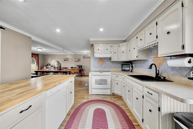 kitchen featuring white appliances, light wood finished floors, a sink, crown molding, and backsplash