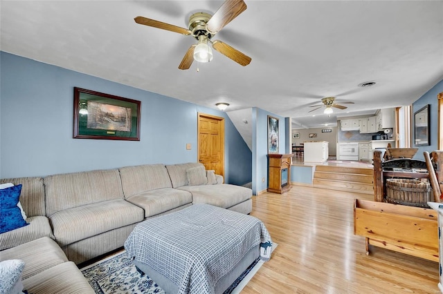 living room featuring light wood-style flooring, visible vents, and ceiling fan