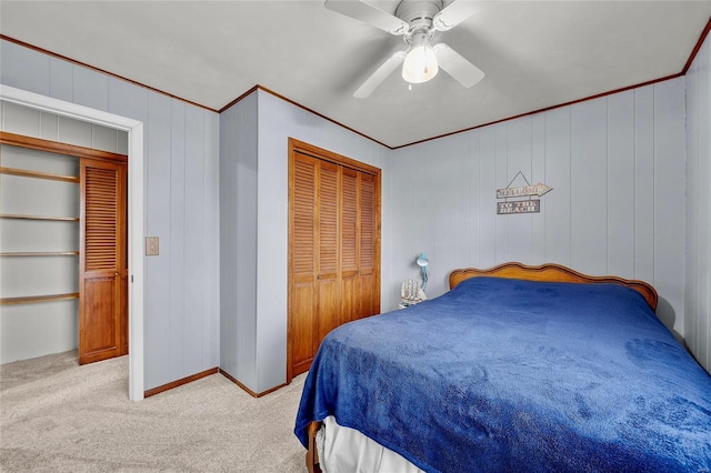 carpeted bedroom with a ceiling fan, a closet, crown molding, and baseboards