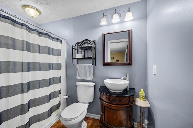 full bath with a textured ceiling, curtained shower, toilet, vanity, and baseboards