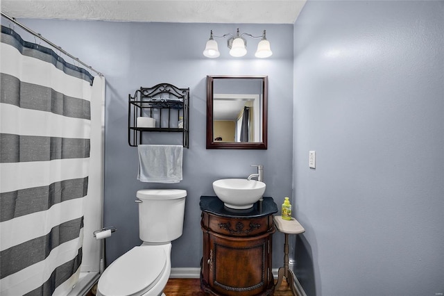 bathroom featuring curtained shower, vanity, toilet, and baseboards