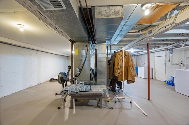 unfinished basement featuring washer / clothes dryer, visible vents, and heating unit