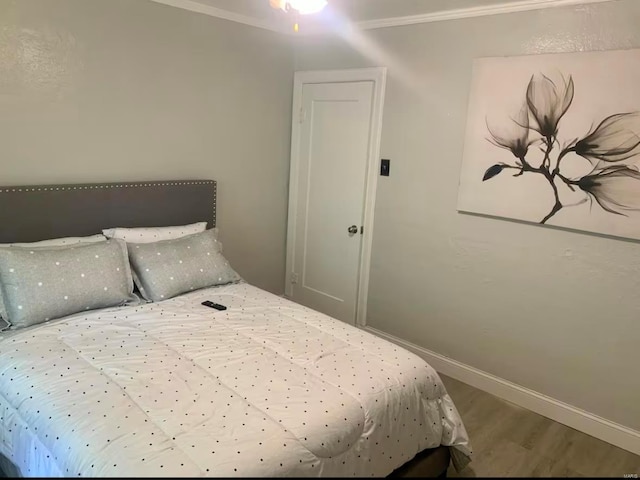 bedroom with crown molding, baseboards, and wood finished floors