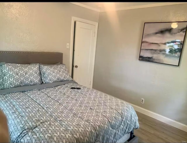bedroom featuring ornamental molding, baseboards, and wood finished floors