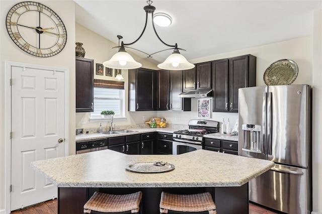 kitchen with under cabinet range hood, a breakfast bar area, stainless steel appliances, and a sink