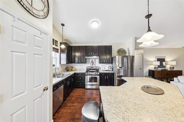 kitchen with decorative light fixtures, dark wood finished floors, stainless steel appliances, a sink, and under cabinet range hood