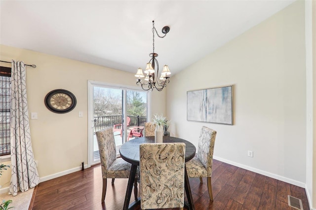 dining space with a chandelier, visible vents, vaulted ceiling, and hardwood / wood-style flooring