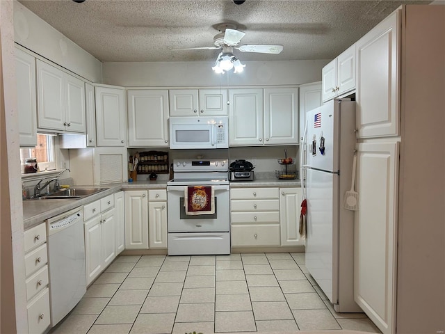 kitchen with light countertops, white cabinets, a sink, light tile patterned flooring, and white appliances