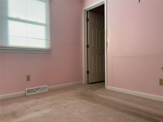 unfurnished room featuring baseboards, visible vents, and light colored carpet