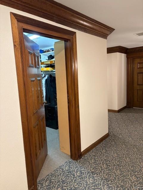 hallway featuring visible vents, crown molding, and baseboards