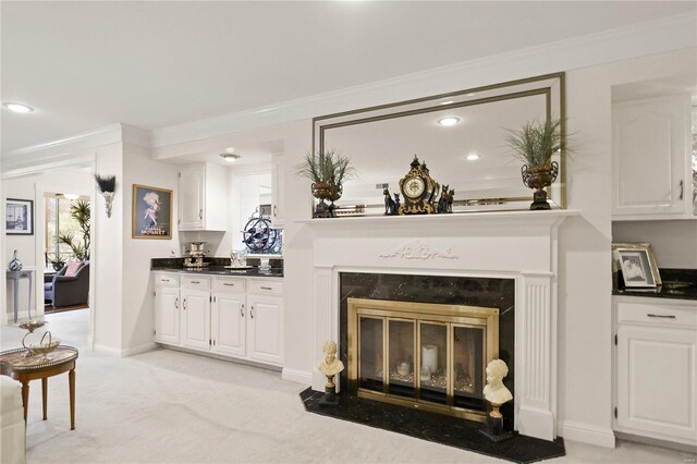 living room featuring crown molding, recessed lighting, a glass covered fireplace, and light colored carpet