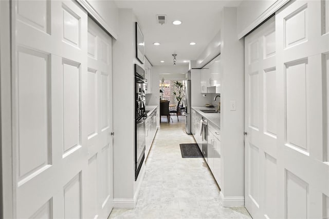 corridor featuring baseboards, a sink, visible vents, and recessed lighting