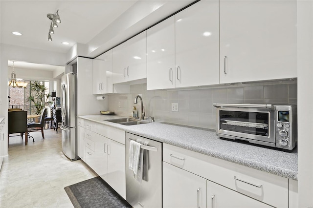 kitchen with a toaster, appliances with stainless steel finishes, light countertops, white cabinetry, and a sink