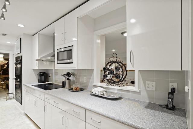 kitchen featuring white cabinets, light countertops, wall chimney range hood, backsplash, and black appliances