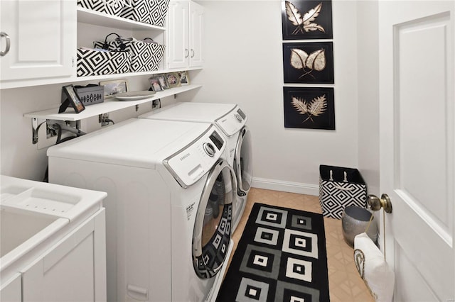 laundry area with light tile patterned flooring, washing machine and dryer, cabinet space, and baseboards