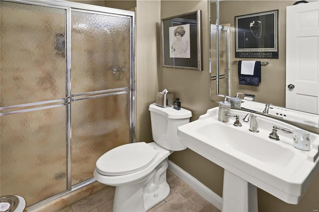 bathroom with a stall shower, tile patterned flooring, a sink, and toilet