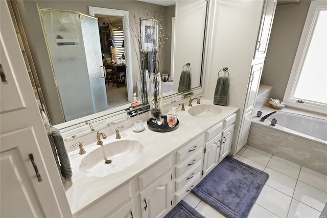 full bathroom with double vanity, a garden tub, a sink, and tile patterned floors