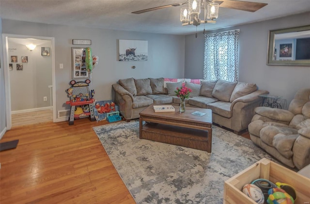 living area with a ceiling fan, a textured ceiling, baseboards, and wood finished floors