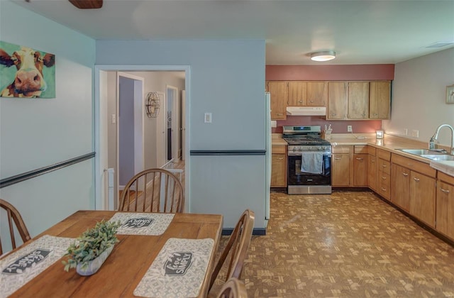 kitchen featuring stainless steel range with gas cooktop, visible vents, light countertops, a sink, and under cabinet range hood