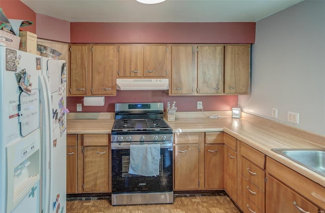 kitchen featuring light countertops, white refrigerator with ice dispenser, gas stove, and under cabinet range hood