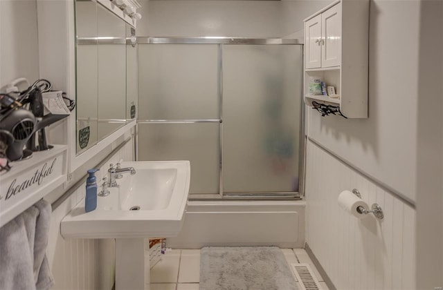 full bathroom with tile patterned flooring, visible vents, bath / shower combo with glass door, and a sink